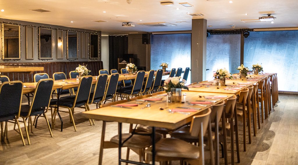 Private function room with long table set up with flowers and cutlery on the table