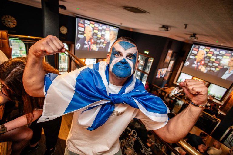 Scotland fan wearing a Scotland flag with a Scotland flag painted on his face